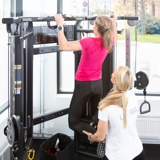 Personlig trening i Lillestrøm – kvinne trener pull-ups med veiledning fra PT